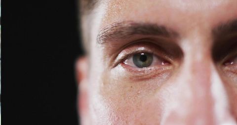 Close-up of mid adult man's green eye texture on dark background