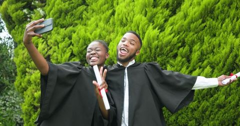 Graduating Friends Taking Selfie Outdoors with Diploma