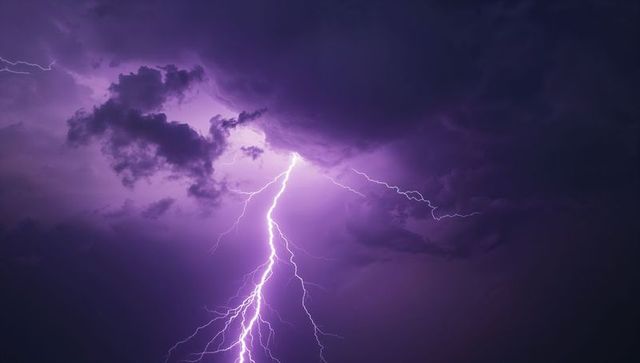 Dramatic lightning bolt during night storm purple sky