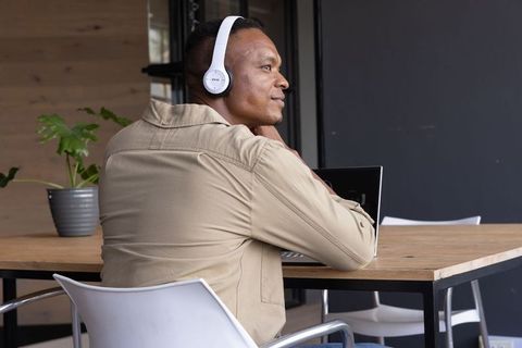 African American man wearing headphones working on laptop in modern office workspace
