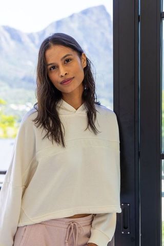 African american woman leaning in doorway with mountain view, cream hoodie and pink sweatpants