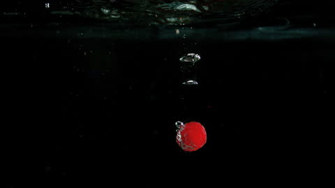 Raspberry Dropping into Water Creating Dramatic Bubbles