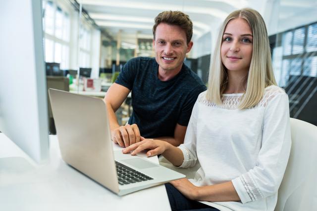 Portrait of male and female graphic designers smiling at camera in office