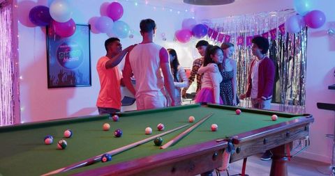 Diverse Friends Celebrating Birthday Party Around Pool Table with Colorful Disco Lights