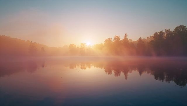 Serene Dawn with Mist Over Tranquil Lake and Forest Silhouettes