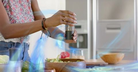 Woman Seasoning Salad in Modern Kitchen