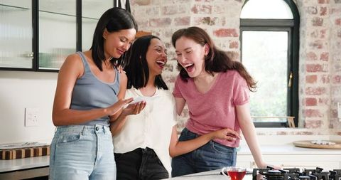 Three friends are gathered in a bright kitchen, exuding happiness and support as one shares her pregnancy excitement. This heartwarming scene, with diverse women laughing together, represents friendship, unity, and celebration of milestones. Useful for illustrating themes of maternity, companionship, and lifestyle. Ideal for blog articles, social media content on friendship stories, or advertisements highlighting women's support networks.
