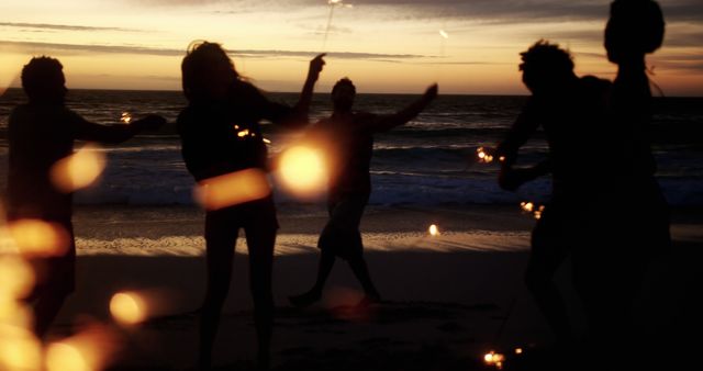 Silhouetted people celebrating with sparklers on the beach during sunset. Perfect for concepts related to summer fun, celebrations, beach parties, and friendship. Can be used in travel magazines, event promotions, and lifestyle blogs to evoke a sense of joy and carefree summer evenings.