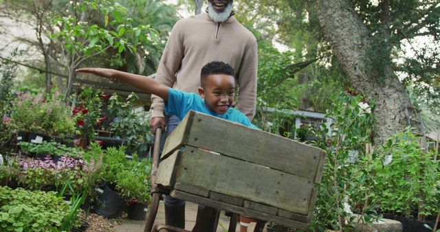 Grandfather and grandson having fun in garden with wooden cart - Download Free Stock Images Pikwizard.com