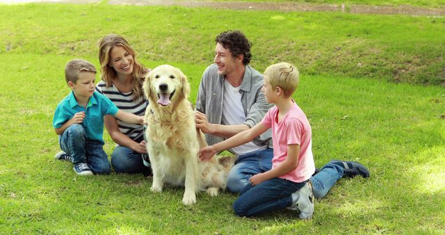 Family of four is sitting on grass in a park, spending quality time with their pet dog on a sunny day. Children are interacting with the dog while parents are smiling, showing warmth and joy. Use this for family life concepts, advertisements featuring outdoor activities, or promoting pet-friendly products.