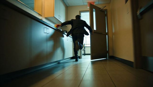 Businessman sprinting through office kitchenette holding orange ball low-angle motion