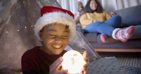 Joyful Child with Christmas Hat Holding Snow Globe at Home