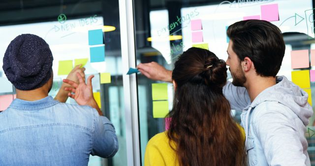 Young Colleagues Discussing Ideas Using Sticky Notes in Modern Office - Download Free Stock Images Pikwizard.com