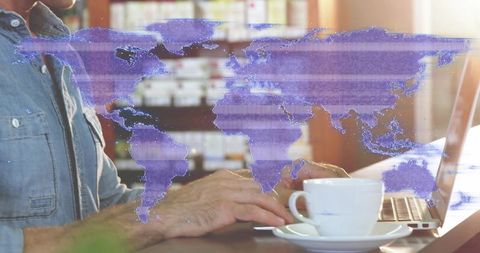 Sunlit cafe laptop with coffee and purple world map overlay, typing remote work concept