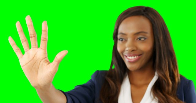 This image shows a woman smiling and waving against a green screen background. Ideal for presentations, advertisements, websites, or social media visuals related to positive interactions, greetings, and friendly gestures. The green screen allows for easy overlay on different backgrounds, making it versatile for various creative projects.