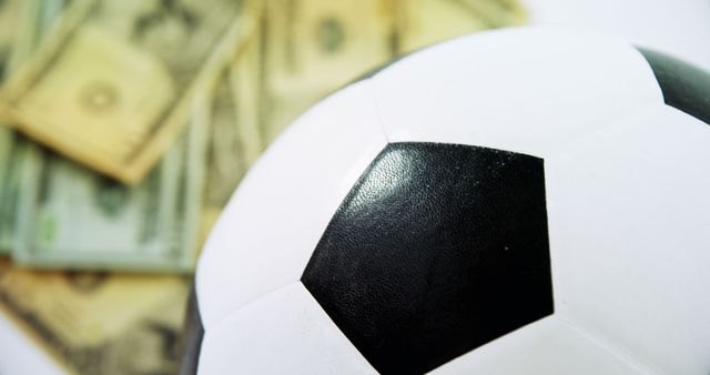 Close-up of a soccer ball with US dollar bills in the background, symbolizing sports financing and investments within the sports industry. Suitable for topics related to sports economics, business in sports, and financial investment in athletics.