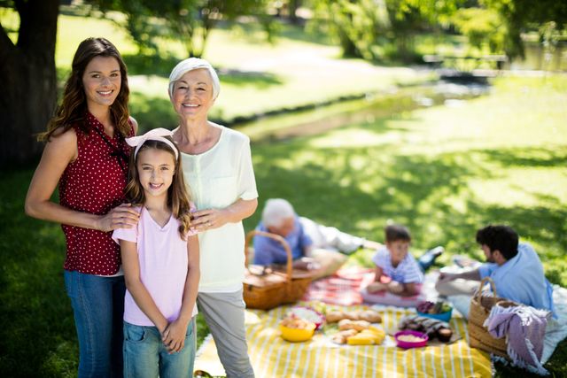 Multi-generational family enjoying a sunny day in park. Ideal for themes of family bonding, outdoor activities, relaxation, and summertime. Perfect for use in marketing materials emphasizing family values, leisure time, or outdoor recreation.