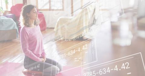 Woman kneeling meditating on pink mat in sunlit living room with data overlay and calm