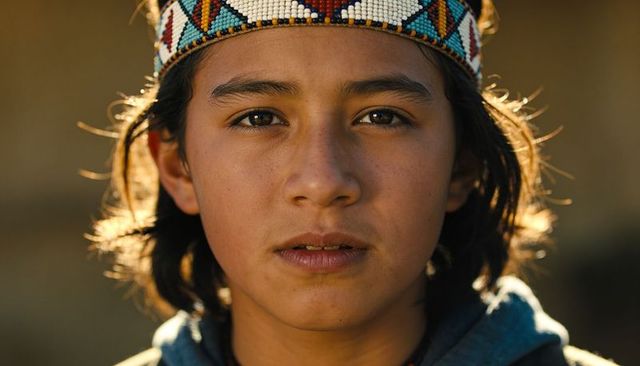 Sunlit teen wearing geometric beadwork headband close-up portrait with golden rimlight