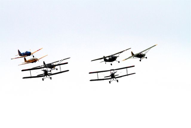 Vintage planes in formation flying create a sense of nostalgia and showcase teamwork and precision in aviation. Perfect for articles or advertisements related to aviation history, airshows, or appeals to aviation enthusiasts.