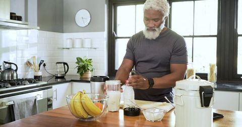 Senior Man Preparing Nutritional Supplement in Modern Kitchen
