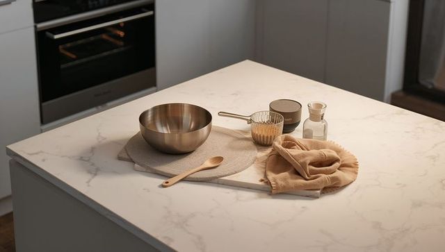 Minimalist kitchen countertop styling with stainless mixing bowl, wooden spoon, neutral linens