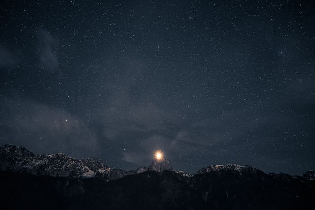 Gorgeous star-filled night sky above stunning snowy mountain peaks. Ideal for use in travel brochures, outdoor adventure campaigns, and nature-themed calendars, capturing the serenity and majesty of the natural world.