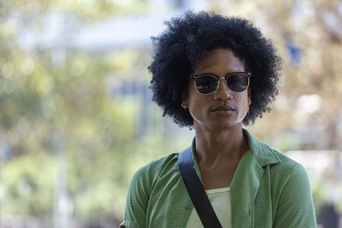African american man standing in urban plaza wearing sunglasses and green shirt, candid street portr