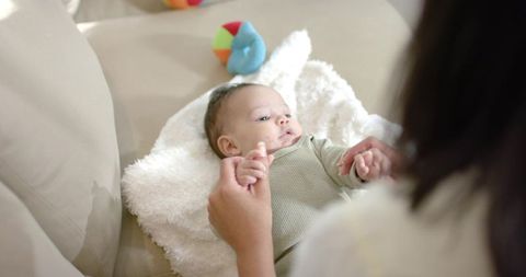 Caregiver Holding Hands with Infant on Comfortable Sofa