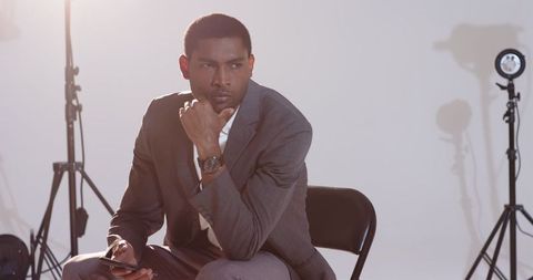 Confident businessman reflecting amid studio lights