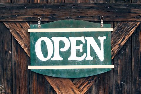 Rustic green open sign on weathered wooden door
