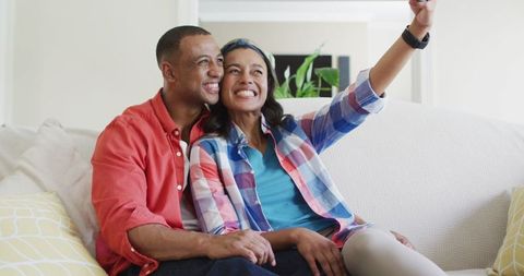 Smiling Couple Embracing on Sofa Taking Selfie