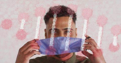 Man holding light blue face mask covering mouth, healthcare awareness studio portrait