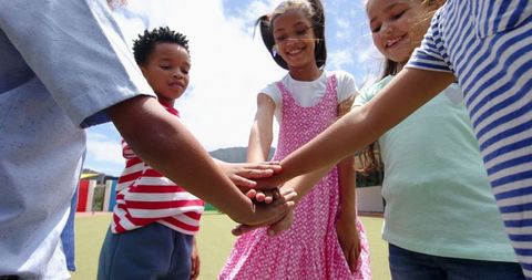 Children Displaying Teamwork with Stacked Hands in Schoolyard