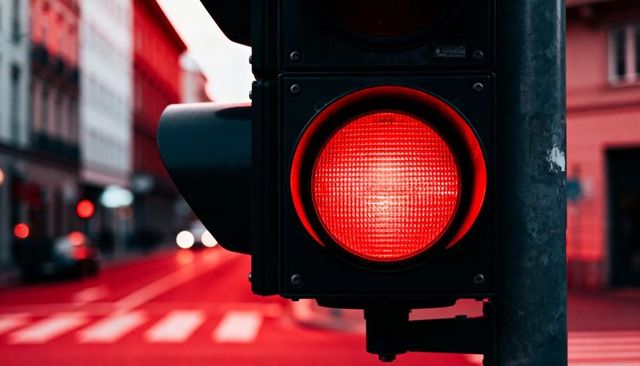 Close-up red traffic light at urban intersection dusk with crosswalk and city bokeh