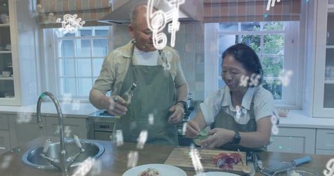 Mature couple cooking together on kitchen island chopping greens and preparing meal