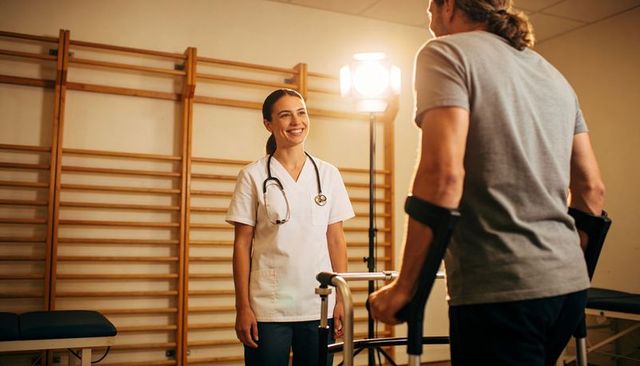 Smiling nurse helping man use walker during rehabilitation session, compassionate care