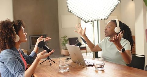 Recording lively podcast conversation between two female cohosts in modern home studio