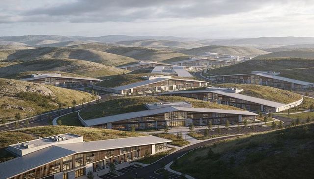 Aerial panning showcasing sustainable campus with green roofs, glass facades and curving roads
