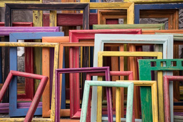 Perfect for home decor blogs, lifestyle publications, and DIY craft tutorials. This vibrant arrangement of multicolored, rustic wooden picture frames makes a lively, eye-catching background for design projects or artistic displays.