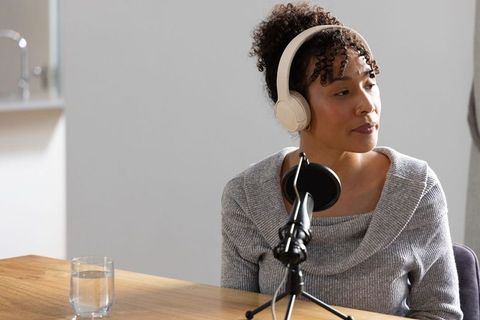 African american woman recording podcast with beige headphones and microphone
