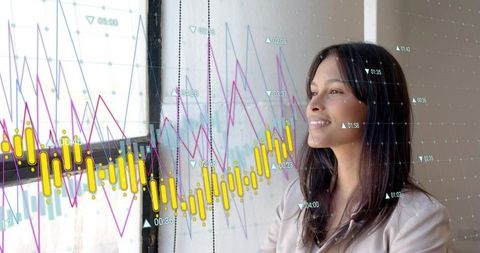 Asian business analyst standing by window studying financial charts and market analytics