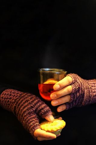 Handmade mittens holding warm drink and mince pie