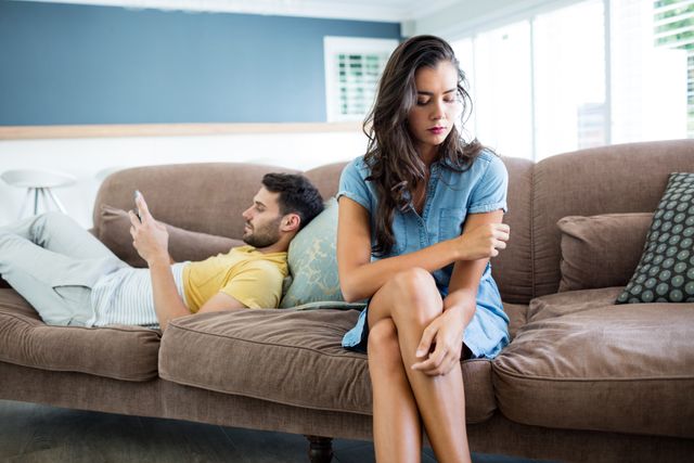 Couple ignoring each other in living room at home