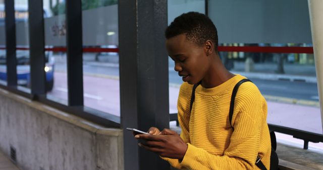 Young Man Waiting at Bus Stop Using Smartphone - Download Free Stock Images Pikwizard.com