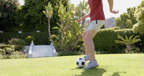 Young Man Practicing Football Tricks in Sunny Garden