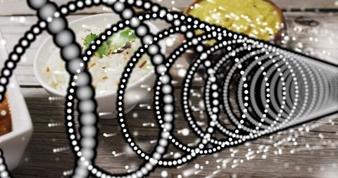 Dotted spiral overlay framing rustic wooden tabletop with white rice bowl and sauces