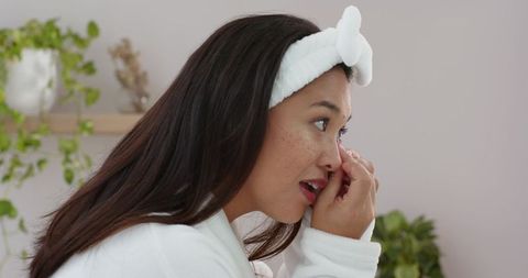 Woman Gently Removing Contact Lens in Serene Bathroom Setting