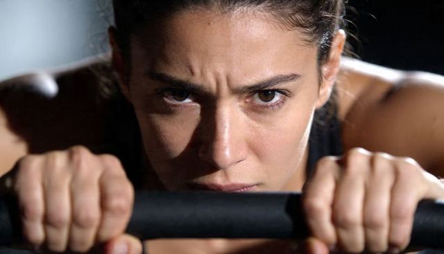 Focused woman gripping padded bar during intense strength training and conditioning