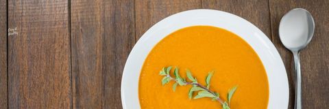 Healthy pumpkin soup with herbal garnish in white bowl